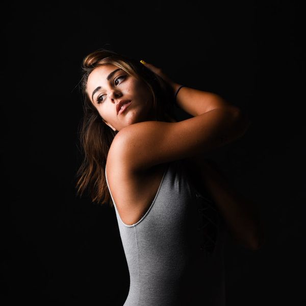 Silhouette of a woman stretching gracefully against a pink and dark background.